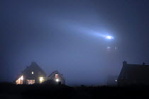 The Cocksdorp lighthouse shining at night in thick fog, Texel, the Netherlands, April 2009