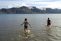 Tourists wade out to swim in geothermal water, Deception Island, Antarctic Peninsula, Antarctica, February 2006
