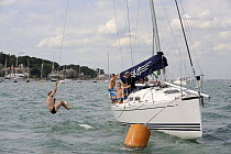 Man swinging from a rope off ^Turbulence II^, Cowes Week, August 2009.