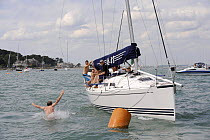 Man swinging from a rope and jumping into the sea off "Turbulence II", Cowes Week, August 2009.