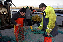 Skipper and mate of fishing trawler "Demares" mending nets. Cullivoe, Unst, Shetland, April 2008.