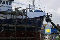 Man painting fishing vessel "Arkh Angell" from a crane on Peterhead slipway, Scotland 2008.