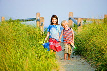 A young brother and sister walking back from the beach at Center Hill Preserve beach, Plymouth, Massachusetts, USA. Model Released. May 2008