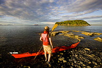 Kayaker about to enter the water, Porcupine Islands, Acadia National Park, Maine, USA. Model Released. June 2008
