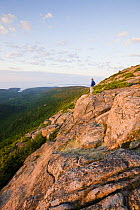 A lone hiker near the summit of Cadillac Mountain at dawn, Acadia National Park, Maine, USA. Model Released. July 2008