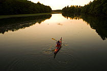 A woman kayaking on the upper reaches of the York River at high tide, sunset, York, Maine, USA. Model Released. May 2008