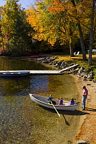 Man launches his three daughters in a rowing boat at Oliver Lodge, Lake Winnipesauke, Meredith, New Hampshire, USA. Model Released. October 2007