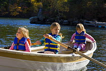 Three young girls (ages 3, 5, 9) in a rowing boat at Oliver Lodge, Lake Winnipesauke, Meredith, New Hampshire, USA. Model Released. July 2008