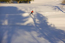 Looking down on a man cross-country skiing (track skiing) on a groomed trail next to the frozen Ottauquechee River in Quechee, Vermont, USA. Model Released.