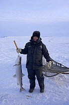 Young Inupiaq woman with Sheefish (Stenodus leucichthys nelma) caught through a hole in pack ice over the Chukchi Sea, for the village elders of Kotzebue, Alaska, March 2008