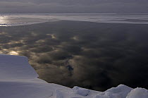 Sun behind storm clouds reflecting in open lead in pack ice, Chukchi Sea near Point Hope, Alaska, March 2008
