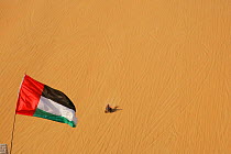 Dune buggy driving down high sand dune and UAE flag, Liwa Oasis, United Arab Emirates, UAE, December 2007