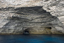 Limestone coastline, with one of the boats that cross to and from the Lavezzi Islands (approximately 10km SE) in the back of a cave, Bonifacio, Corsica, France, September 2008