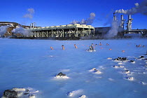 People bathing in the spa waters of the Blue Lagoon with the geothermal power plant in the background, Grindavik, Iceland 2005