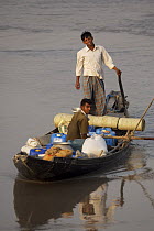 Men in boat with containers of shrimp fry. Khulna Province, Bangladesh. March 2006