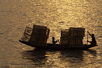 Boys transporting fishing traps by boat on the Kholpatura River, Sundarbans, Khulna Province, Bangladesh, March 2006