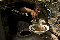 Honey collector pouring out a bowl of honey to give to the photographer, Sundarbans, Khulna Province, Bangladesh, April 2006