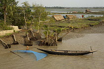 A net is set for catching shrimp fry along the Passur River. Mud and thatch houses of shrimp fry fisherman and shrimp ponds visible in the background, Sundarbans, Khulna Province, Bangladesh, April 20...