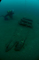 Diver working near the uncovered hull of an unidentified sailing ship off the south coast, UK.. September 2009.