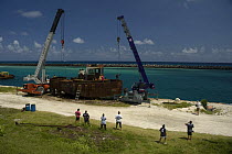 Cranes being rigged to the hulk of tugboat ''Blue Plunder'' prior to towing out to sea and sinking. Nassau, Bahamas. August 2007.