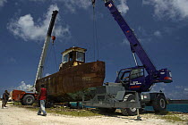 Cranes being rigged to the hulk of tugboat ''Blue Plunder'' prior to towing out to sea and sinking. Nassau, Bahamas. August 2007.