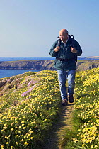 Man hiking along on clifftop footpath (The South West Coastal Path) in spring, Bedruthan Steps, Cornwall, England, May 2005, model released