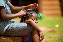 Woman decorates child's hair at home for homeless women and orphans, Tananarive, Madagascar, October 2006
