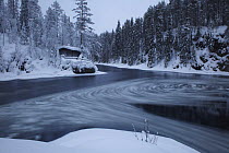 Whirlpool with ice in water, small hut on bank, Kitkajoki River, Oulanka National Park, Finland, February 2009
