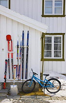 Bicycle, shovel and skis outside traditional wooden building, Dovrefjell National Park, Norway, April 2009