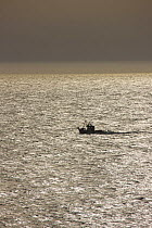 Fishing boat on glistening sea, near Conil de la Frontera, Costa de la Luz, Andalucia, Spain, March 2008
