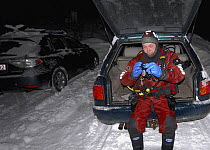Photographer, Magnus Lundgren, sitting in car boot wearing diving gear, Trondheimsfjorden, Norway, February 2009