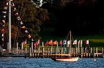 Small sailing boat moored off pontoon with country flags and signal-flag bunting. Rhode Island, USA, 2009.