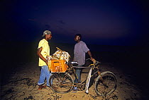 Fishermen use bicycle to transport fish to market at dusk, Inhassoro, Mozambique, November 2008