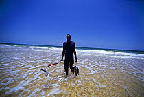 Spearfisherman comes out of the sea with catch of Sea Perch and Parrot Fish, Inhassoro, Mozambique, November 2008