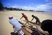 Fishermen drag rowing boat up the beach on return from a day of line fishing, Tofo, Mozambique, November 2008