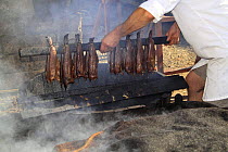 Smoked Haddock, "Arbroath Smokies" being removed from bar of rel-kiln in which they were cured. Moray Firth, Scotland. July 2009.