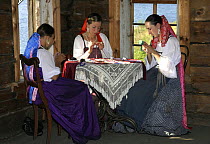 Woman dressed up in traditional costume, sewing embroidery, in wooden museum on Kizhi Island, Lake Onega, Karelia, N Russia, September 2007.