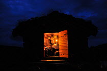 Photographer, Vincent Munier, sitting in small traditional cabin with a grass roof, at night, Forollhogna National Park, Norway, on location for Wild Wonders of Europe, September 2008