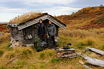 Photographer, Vincent Munier, and Laurent Joffrion, standing outside small traditional grass roof hut, Forollhogna National Park, Norway, on location for Wild Wonders of Europe, September 2008