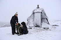 Photographer, Vincent Munier, outside small hut with rucksacks in snow, Forollhogna National Park, Norway, on location for Wild Wonders of Europe, September 2008