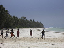 Masaai men playing football on beach, Bwejuu, Zanzibar, Tanzania. August 2008.