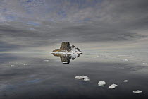 Island with reflection in calm sea, Svalbard, Norway, June 2009