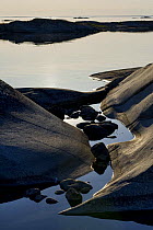 Coastal rocks with reflections at sunset, Kallskr, Stockholm Archipelago, Sweden, June 2009