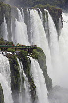 People on viewing platform dwarfed by Iguazu falls, Iguacu National Park, Argentina February 2009
