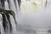 Tourists on viewing platform dwarfed by Iguazu falls including Garganta del Diablo (Devil's throat), Iguacu National Park, Argentina February 2009