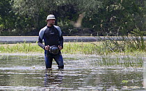 Photographer, Ruben Smit, standing in water with camera, Gornje Podunavlje Special Nature Reserve, Serbia, June 2009