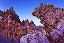 Paternkofel (left) and Tre Cime di Lavaredo mountains at dawn seen behind rocks, Sexten Dolomites, South Tyrol, Italy, Europe, July 2009