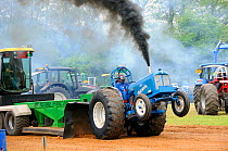 High powered tractor competing in a "tractor pull" competition to drag a weighted sledge as far as possible, North Somerset show, Wraxall, Nr Bristol, UK. May 2009
