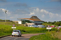 View of Cley reserve, Norfolk Wildlife Trust, showing coastal road, visitor centre with sedum roof and wind turbine, UK, May