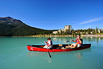 Two people canoeing on Lake Louise, a hotel on the shore, Banff National Park, Rocky Mountains, Alberta, Canada, September 2009